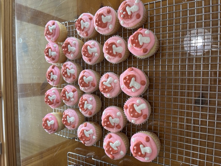 Pink-frosted cupcakes topped with red mushroom decorations on a cooling rack