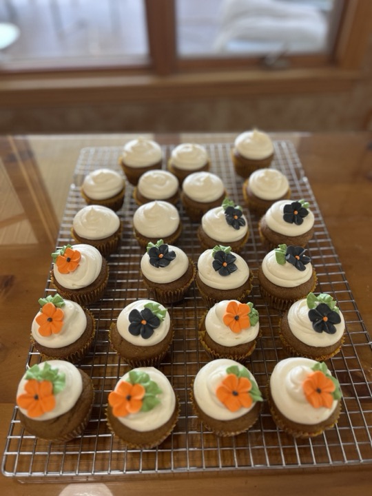 White-frosted cupcakes decorated with black and orange frosting flowers