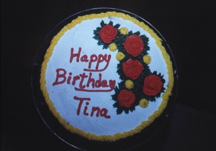 Round white birthday cake with red roses and yellow border