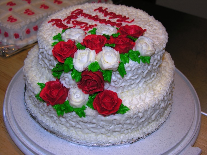 Two-tier white anniversary cake with red and white frosting roses
