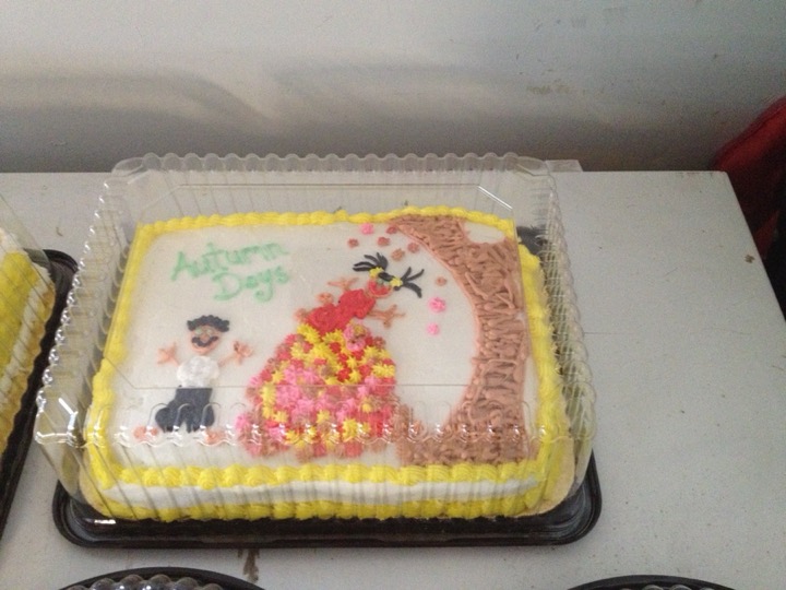 White sheet cake with autumn tree and leaf-skirt illustration in frosting