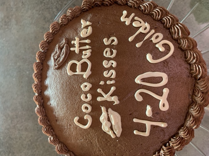 Round chocolate cake with piped off-white message and kiss motifs
