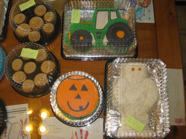 John Deere tractor cake, mummy cake, jack-o-lantern cake, and cupcakes in packaging
