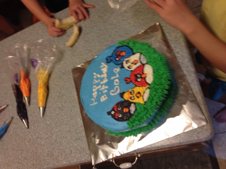 Blue birthday cake decorated with Angry Birds characters and green grass border