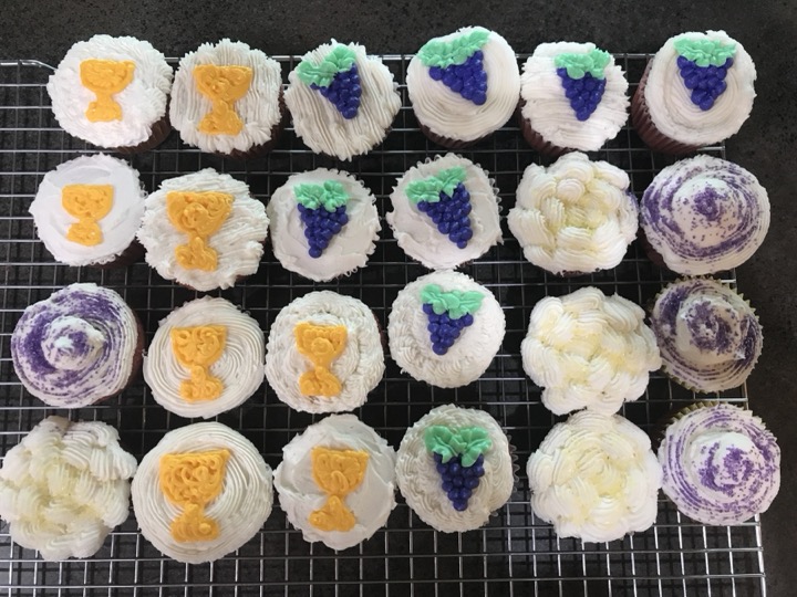 Cupcakes decorated with chalices, grape clusters, and white floral swirls